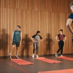 A group exercise class with a personal trainer leading stretching exercises in a gym.